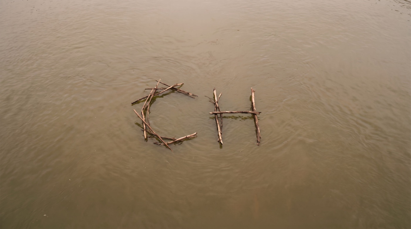 The letters CH built from sticks, floating on water