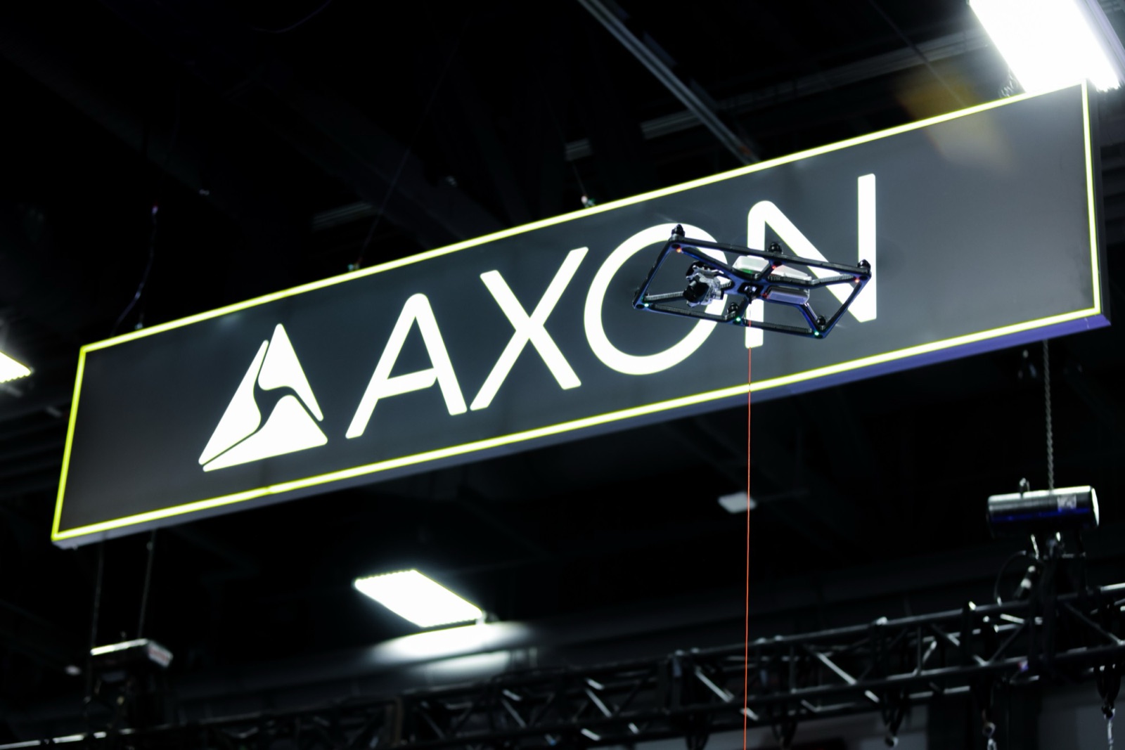 A tethered drone hovering in front of the Axon sign