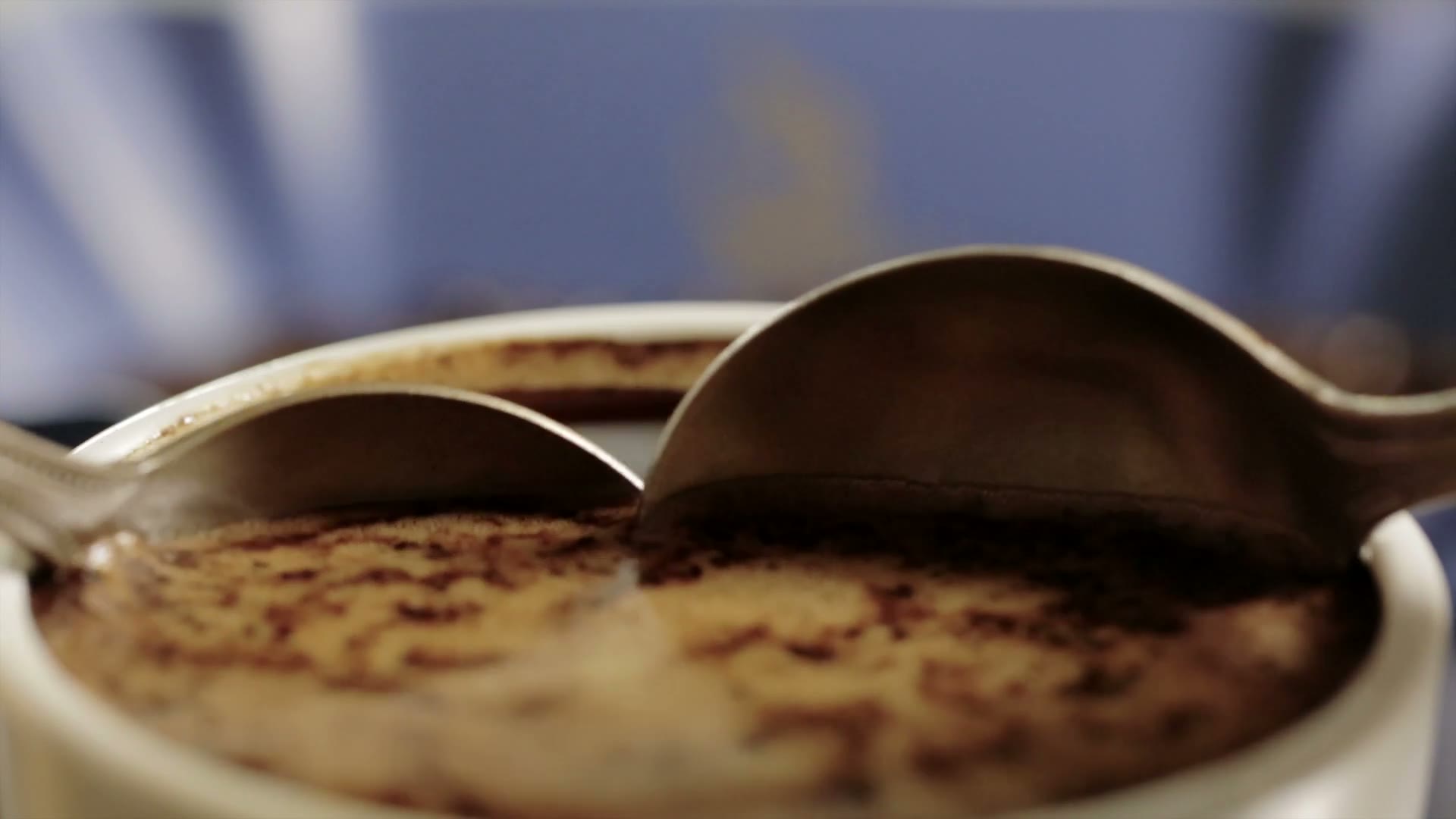 Spoons breaking the crust on cupping bowls