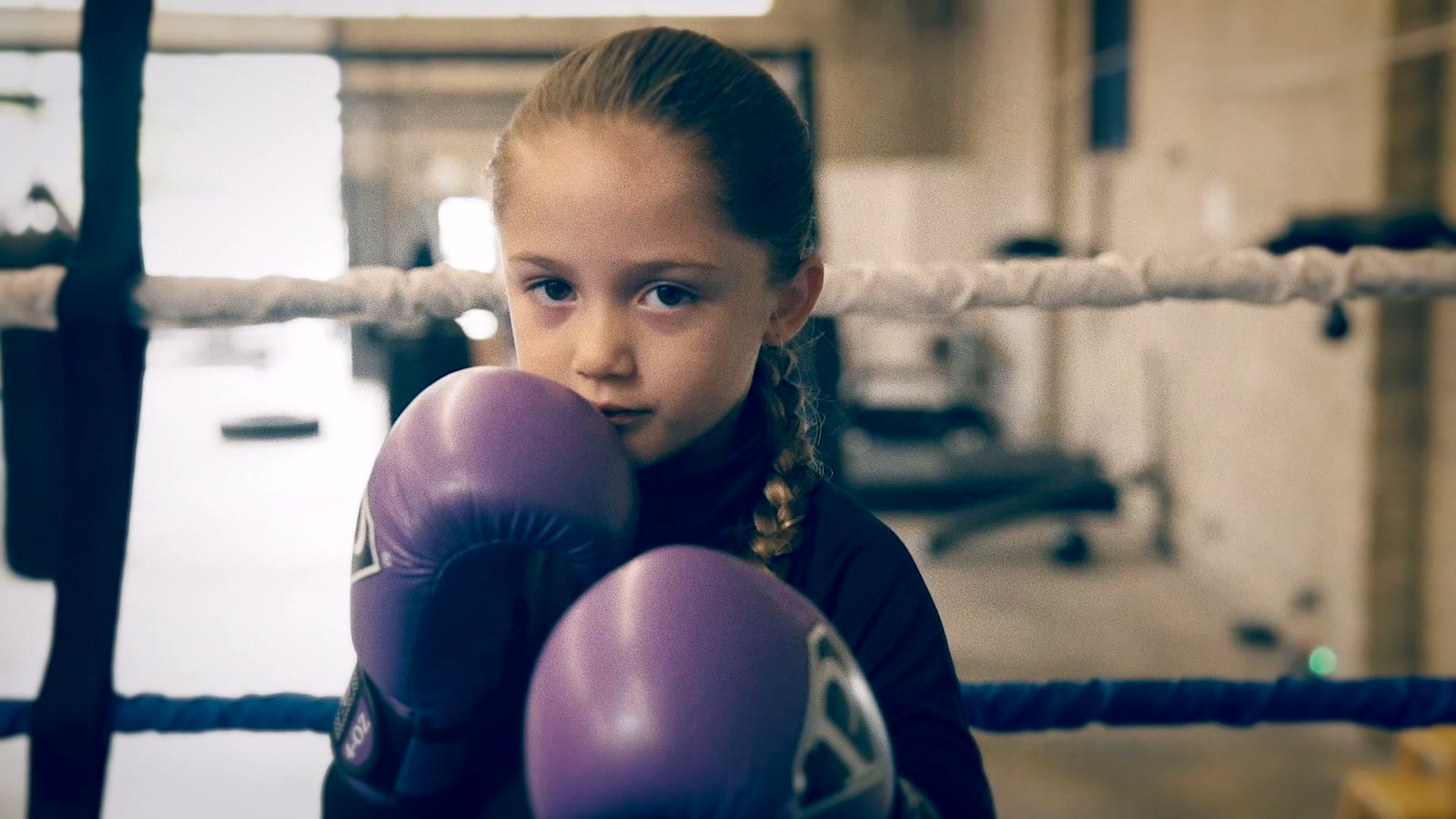 A young boxer in purple gloves in the ring